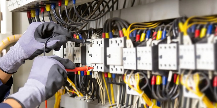 Electrician testing a commercial control panel with a multimeter